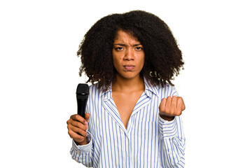 Young African American singer woman holding a microphone isolated showing fist to camera, aggressive facial expression.