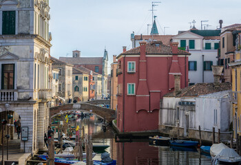 Chioggia cityscape with narrow water canal with moored boats, buildings - Venetian lagoon, Venice province, Italy - October 30, 2021