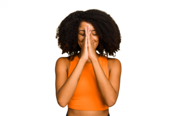 Young African American woman isolated holding hands in pray near mouth, feels confident.