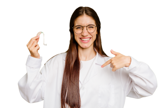 Young otorhinolaryngologist caucasian woman holding hearing aid isolated person pointing by hand to a shirt copy space, proud and confident