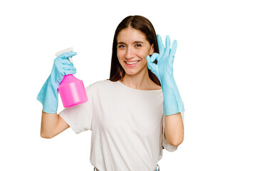 Young cleaner woman isolated cheerful and confident showing ok gesture.