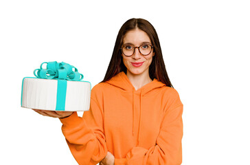 Young caucasian woman holding a birthday cake isolated laughing and having fun.