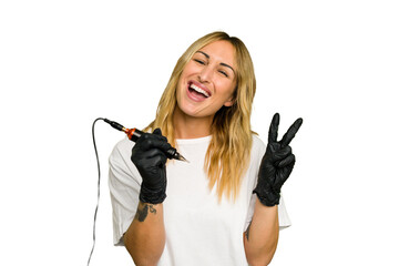 Tattoo artist caucasian woman isolated on green chroma background joyful and carefree showing a peace symbol with fingers.