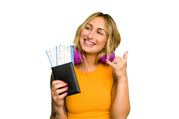 Young caucasian woman with inflatable travel pillow holding passport isolated on green chroma background showing a mobile phone call gesture with fingers.