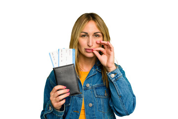 Young caucasian woman holding a passport isolated on green chroma background with fingers on lips keeping a secret.