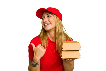 Young caucasian delivery woman holding a burger isolated on green chroma background points with...
