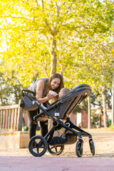 Obraz premium Mother feeding her son with a milk bottle in the park inside the baby stroller