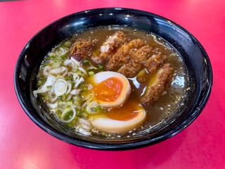 Japanese Food Style : Homemade Shoyu ramen with fried pork Tonkatsu , boiled egg , put in the black bowl and place on the table.
