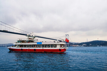 Fototapeta na wymiar A passenger ferry passing under the Istanbul Bosphorus Bridge.