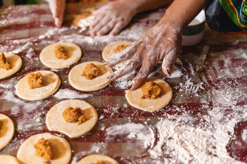 Imagen horizontal de las manos de una madre y su hija preparando algunos bocadillos caribeños...