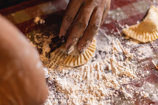 Imagen horizontal de cerca de las  manos de una mujer irreconocible preparando algunas empanadas. 