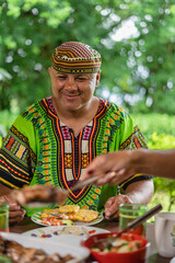 Imagen vertical de un hombre con ropa muy colorida muy sonriente degustando una deliciosa comida...