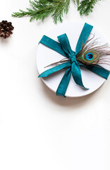 Christmas round white gift box with peacock feather composition. Winter holiday festive greeting card. Copy space	