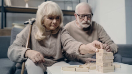 senior couple with dementia playing with wooden blocks in tower game together.