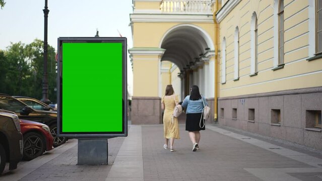 4k Mockup billboard stands and people walk in city spbd. Close view of vertical lightbox for advertising standing by road with cars and pedestrians walking in town on summer day. Beautiful view of