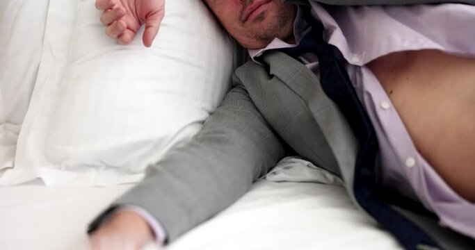 Drunk man in suit sleeping in bed with glass of whiskey in his hand 4k movie slow motion