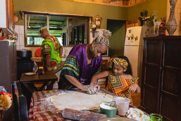 Imagen horizontal de una madre afrocaribeña en el interior de su hogar, cocinando junto a su pequeña hija mientras su padre prepara otro platillo. 