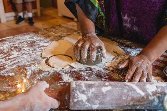 Imagen horizontal de una mujer afrocaribe&ntilde;a irreconocible cortando en forma circular unos trozos de masa para preparar unos bocadillos caribe&ntilde;os. 