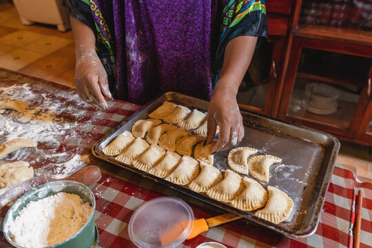 Imagen horizontal de una mujer afrocaribe&ntilde;a irreconocible preparando unas deliciosas empanadas en casa. 