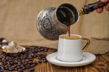 Turkish coffee transferred from the coffee pot to the cup, coffee beans and Turkish delight