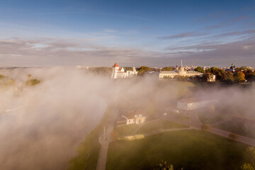 Fototapeta premium earlier foggy morning and aerial panoramic view on medieval castle and promenade overlooking the old city and historic buildings near wide river
