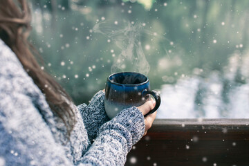 Woman with long brown hair drinking hot tea on snowy day in mountains