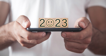Human hand showing 2023 on wooden block.