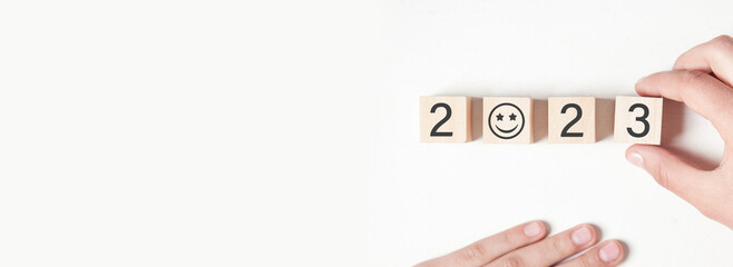 Human hand showing 2023 on wooden cube.