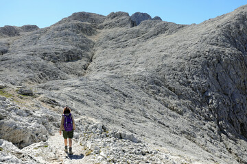 Fototapeta premium Young female hiker walking on the trail in the Italian mountains