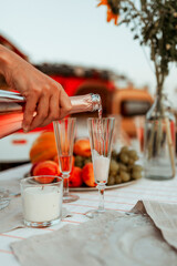 young woman pours pink champagne into a glass in nature by the sea
