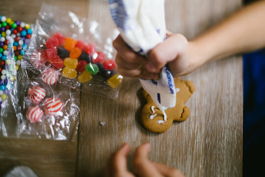 Child decorates gingerbread man with frosting and candy