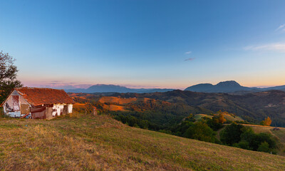 Fototapeta na wymiar Barn on top of hill overlooking deep valley and mountain range on the horizon