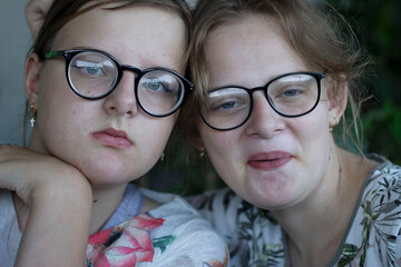 Portrait of two sisters in glasses, teenagers posing in front of the camera