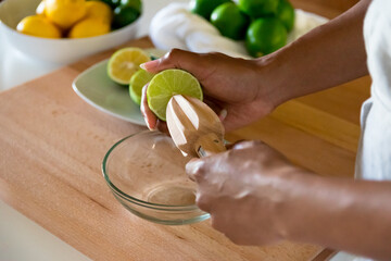 African American woman, Black woman hands juicing lime with a wooden reamer citrus juicer - obrazy, fototapety, plakaty