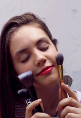 young girl with make-up brushes, portrait of a teenager with problem skin on a white background