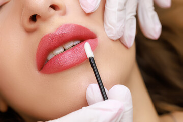 the completed work of permanent makeup of the lips, the master removes the remnants of the pigment...
