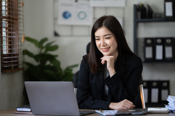 Beautiful smiling young woman working on computer at her workplace in office