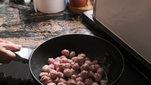 tossing meat balls in a frying pan