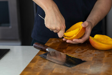 Chef cook cutting fresh mango for fruit salad on wooden cut board