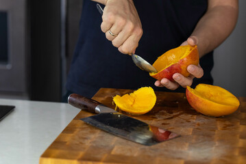 Chef cook cutting fresh mango for fruit salad on wooden cut board