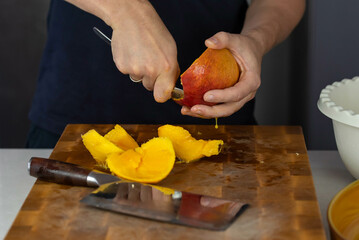 Chef cook cutting fresh mango for fruit salad on wooden cut board