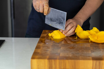 Chef cook cutting fresh mango for fruit salad on wooden cut board