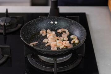 Chef cook hands roasting shrimps in wok pan with oil and spice. Seafood healthy cuisine.