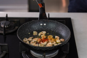 Chef cook hands roasting shrimps in wok pan with oil and spice. Seafood healthy cuisine.