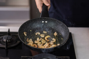 Chef cook hands roasting shrimps in wok pan with oil and spice. Seafood healthy cuisine.