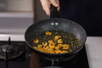 Chef cook hands roasting shrimps in wok pan with oil and spice. Seafood healthy cuisine.