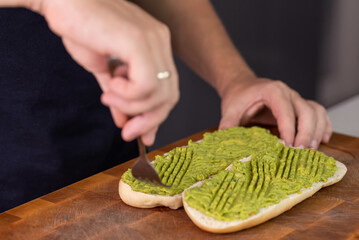 Chef cook hands making fresh diet avocado toast on bread with fork. Vegetarian and vegan cuisine. Healthy vitamin breakfast.