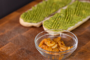 Chef cook hands making fresh diet avocado toast with seafood shrimps. Healthy vitamin breakfast.