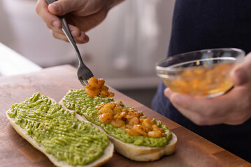 Chef cook hands making fresh diet avocado toast with seafood shrimps. Healthy vitamin breakfast.