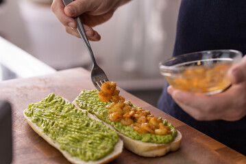 Chef cook hands making fresh diet avocado toast with seafood shrimps. Healthy vitamin breakfast.
